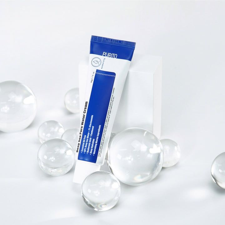 Tube de crème sur socle blanc. Billes de verre. Texte: Deep Sea Pure Water Cream. Marque PURITO. Emballage bleu et blanc.