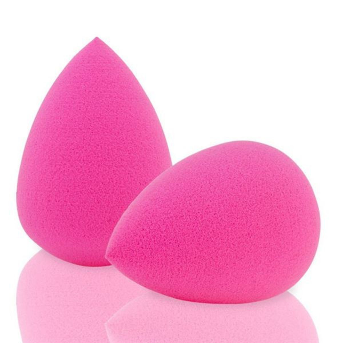 Deux éponges de maquillage rose vif en forme de goutte, sur une surface réfléchissante.