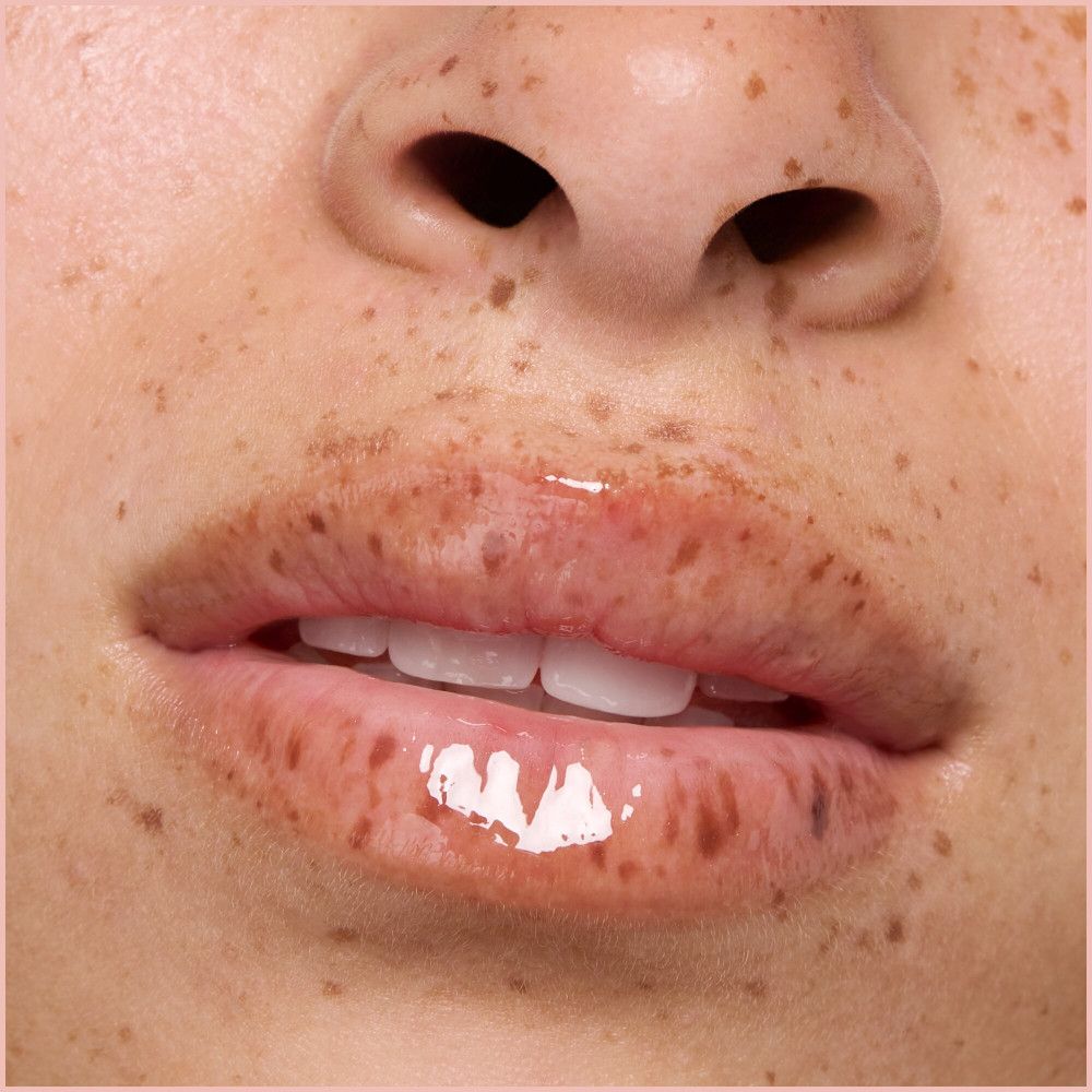 Close-up van lippen met glanzende lipolie. Huid met sproeten.