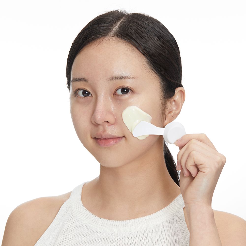 Une femme applique un masque Modeling Pack sur son visage avec une spatule.