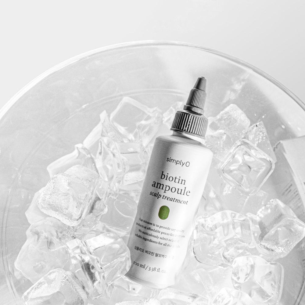 Een fles met zwarte dop in een kom met ijsblokjes. Opschrift: biotin ampoule scalp treatment.