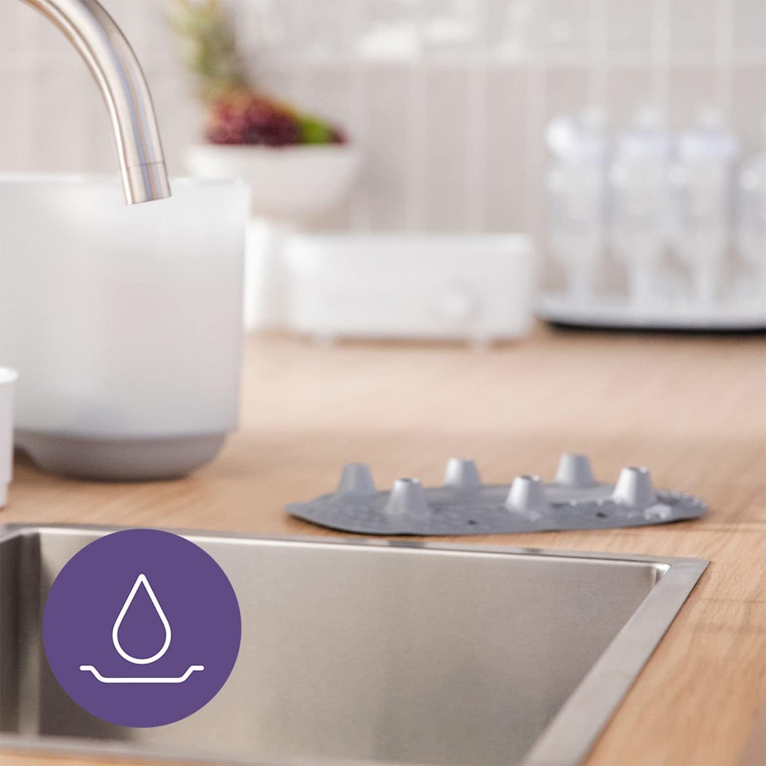 Un symbole de goutte dans un cercle violet au-dessus d'un évier de cuisine, montrant une partie du stérilisateur Philips Avent.