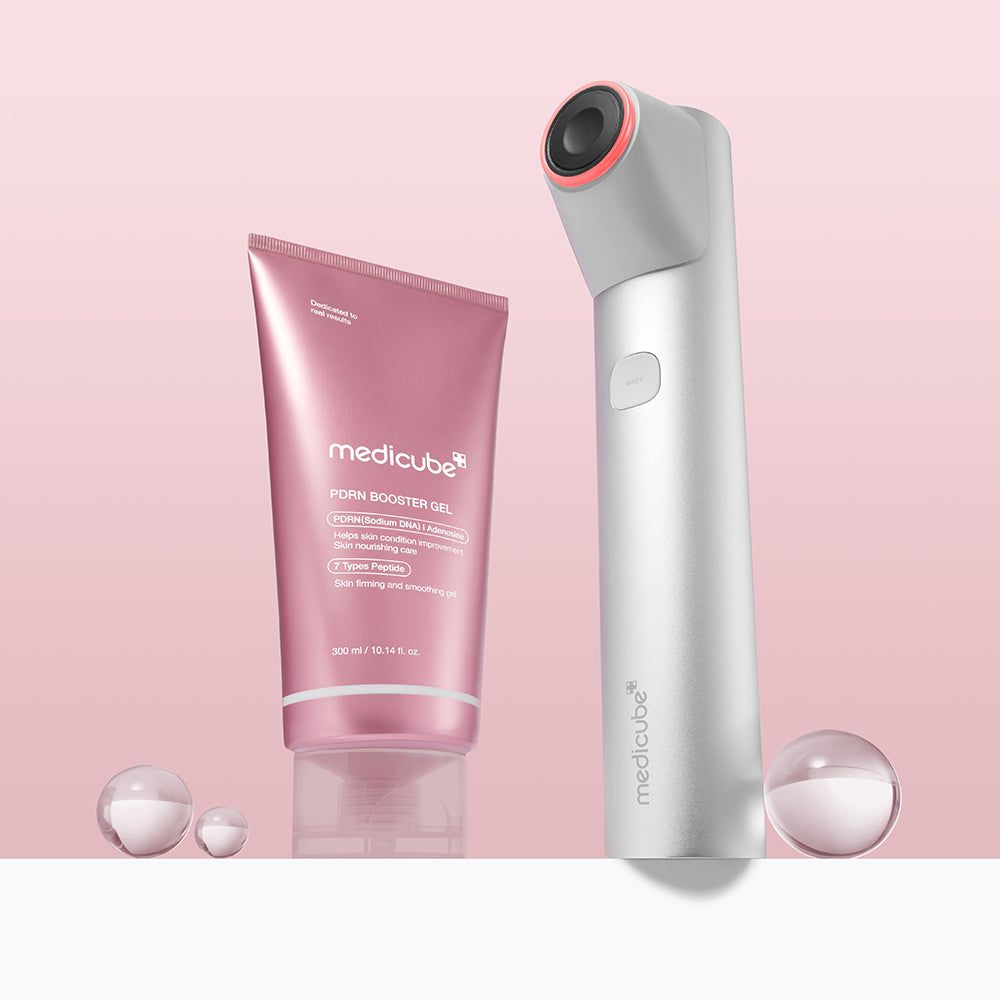 Roze tube MEDICUBE PDRN Booster Gel en een wit apparaat. Twee transparante bollen op de voorgrond.