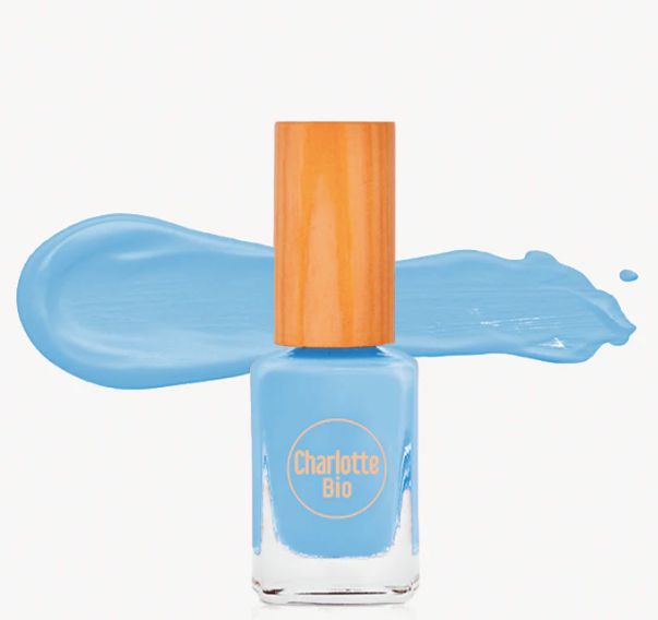 Lichtblauwe nagellak met houten dop. Opschrift "Charlotte Bio". Kleurveeg op de achtergrond.