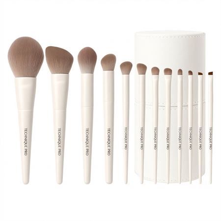 Un ensemble de 10 pinceaux de maquillage blancs avec des poils beiges et un étui rond blanc.