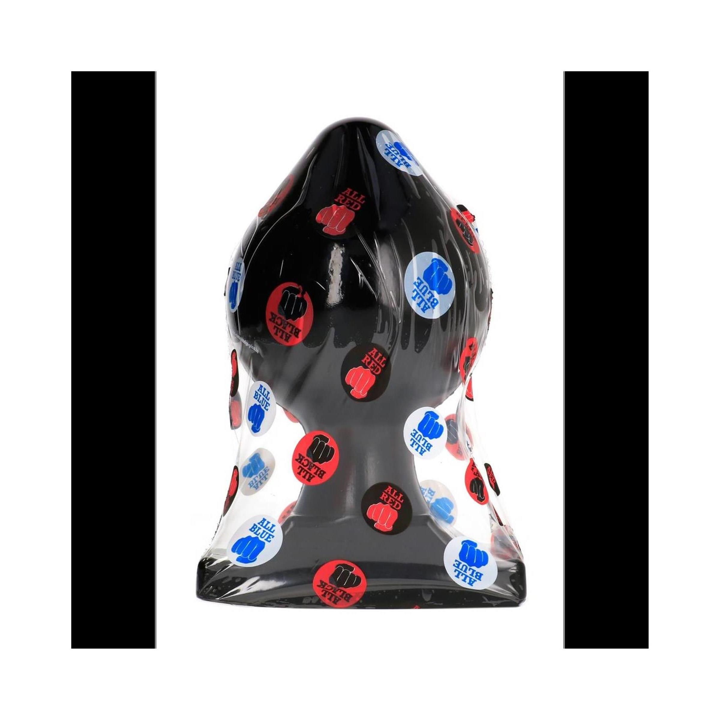 Zwarte anale plug in folie, bedekt met ronde stickers.