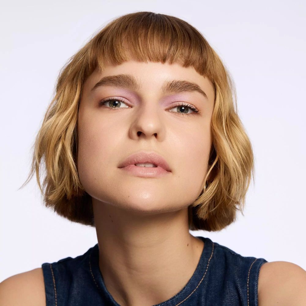 Femme avec une coupe au carré et fard à paupières violet. Regardant la caméra.