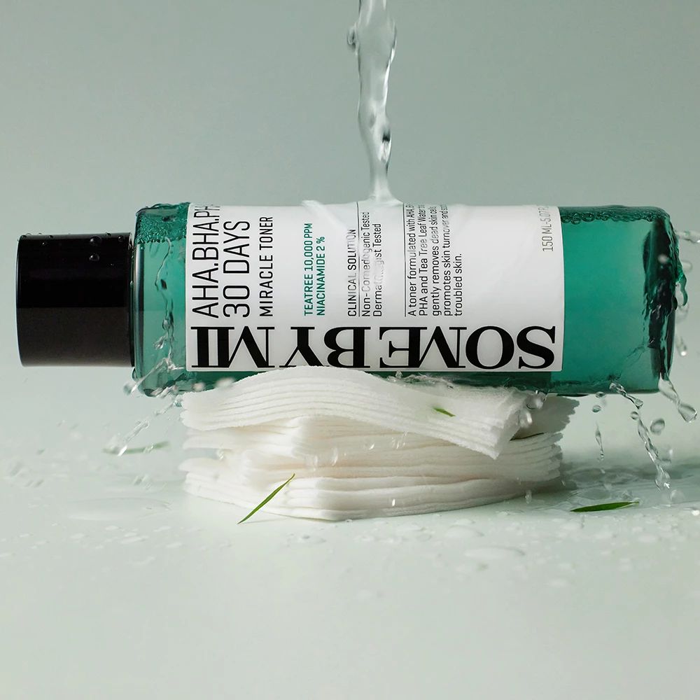 Vloeistof spettert op watjes en fles. Opschrift: AHA-BHA-PHA 30 DAYS MIRACLE TONER. Tekst en logo.