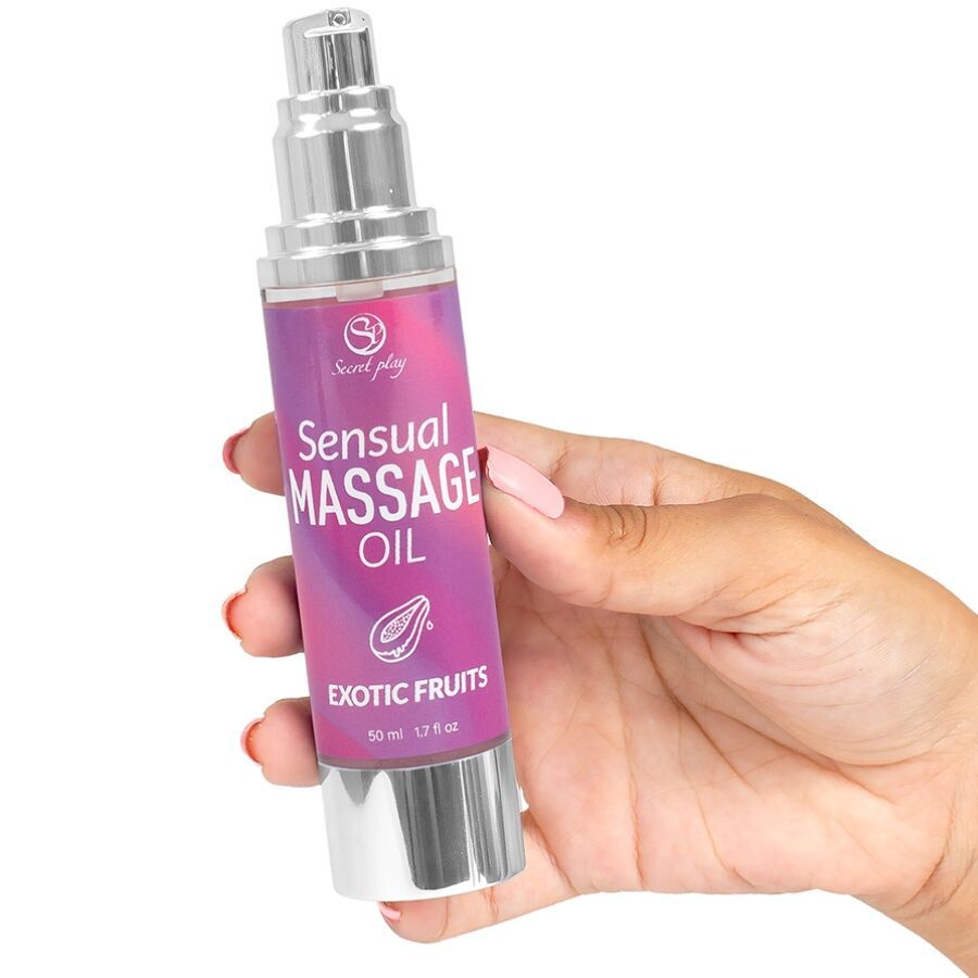 Fles massageolie. Opschrift: Sensual Massage Oil Exotic Fruits. In hand gehouden.