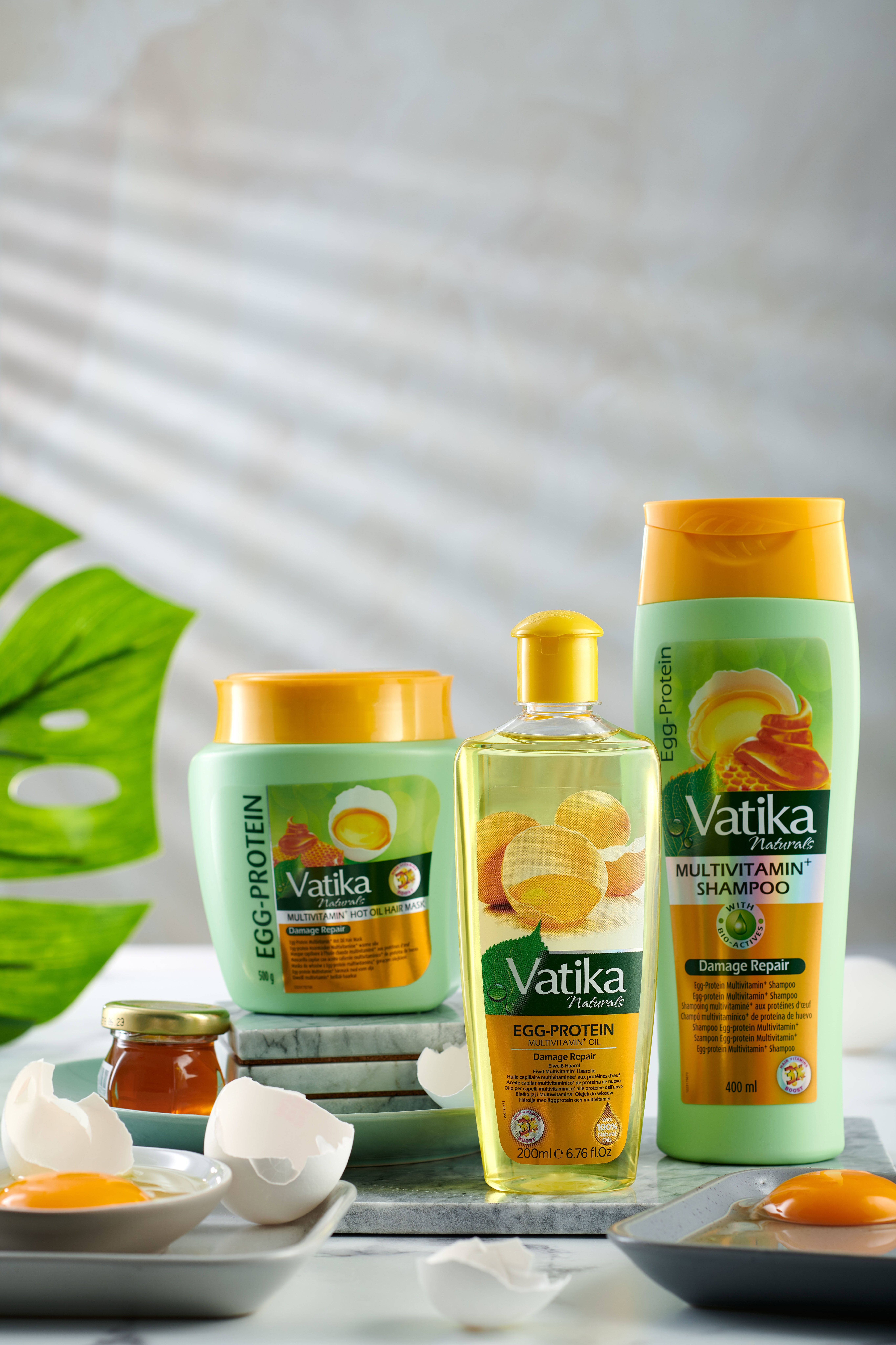 Trois produits Vatika: shampooing, masque capillaire et huile capillaire. Œufs et miel sur une table.