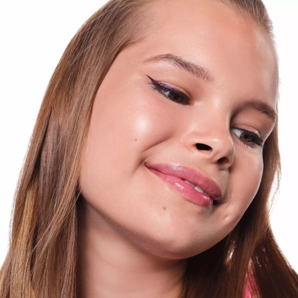 Portrait d'une jeune fille avec un eye-liner violet. Elle sourit.