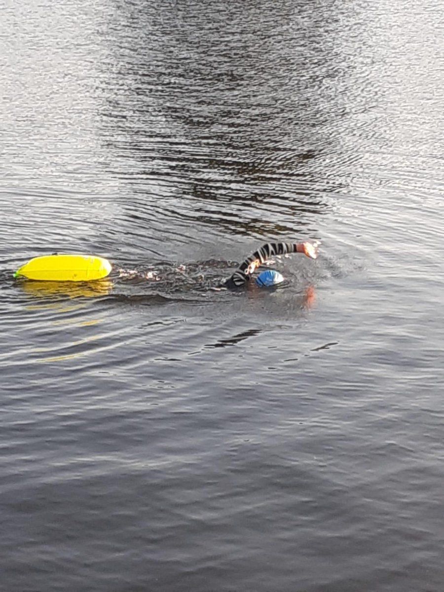 Personne nage dans l'eau, reliée à une bouée jaune. La bouée flotte sur l'eau.