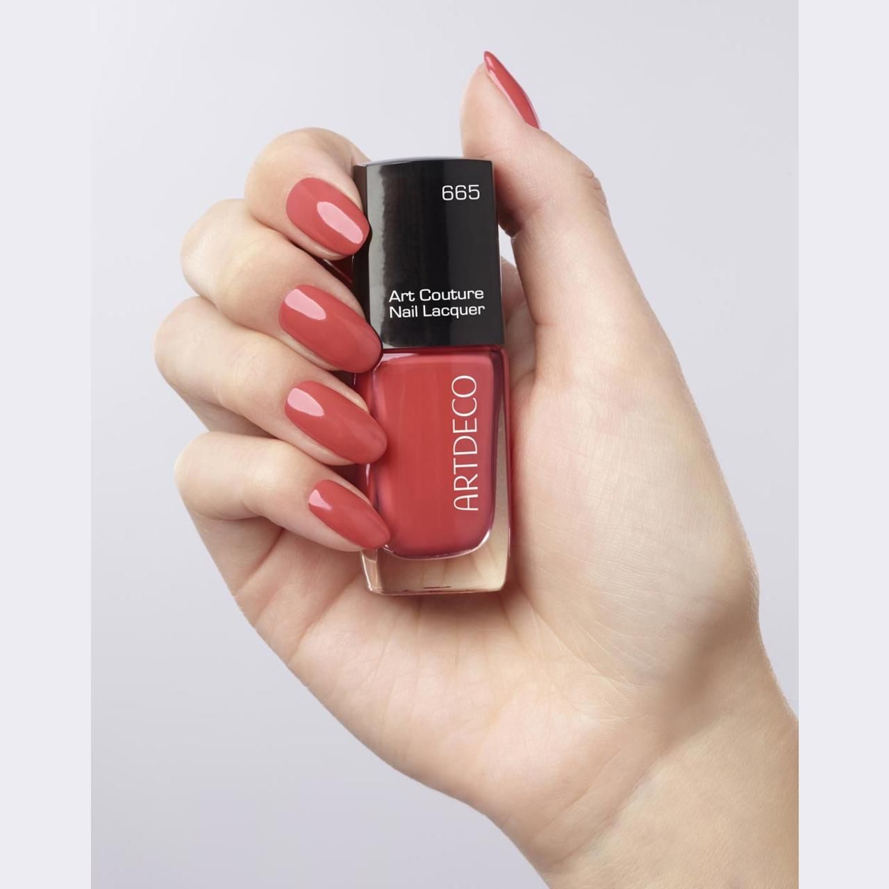 Hand houdt nagellakflesje vast. Nagels gelakt. Opschrift: Artdeco, Art Couture Nail Lacquer, 665.