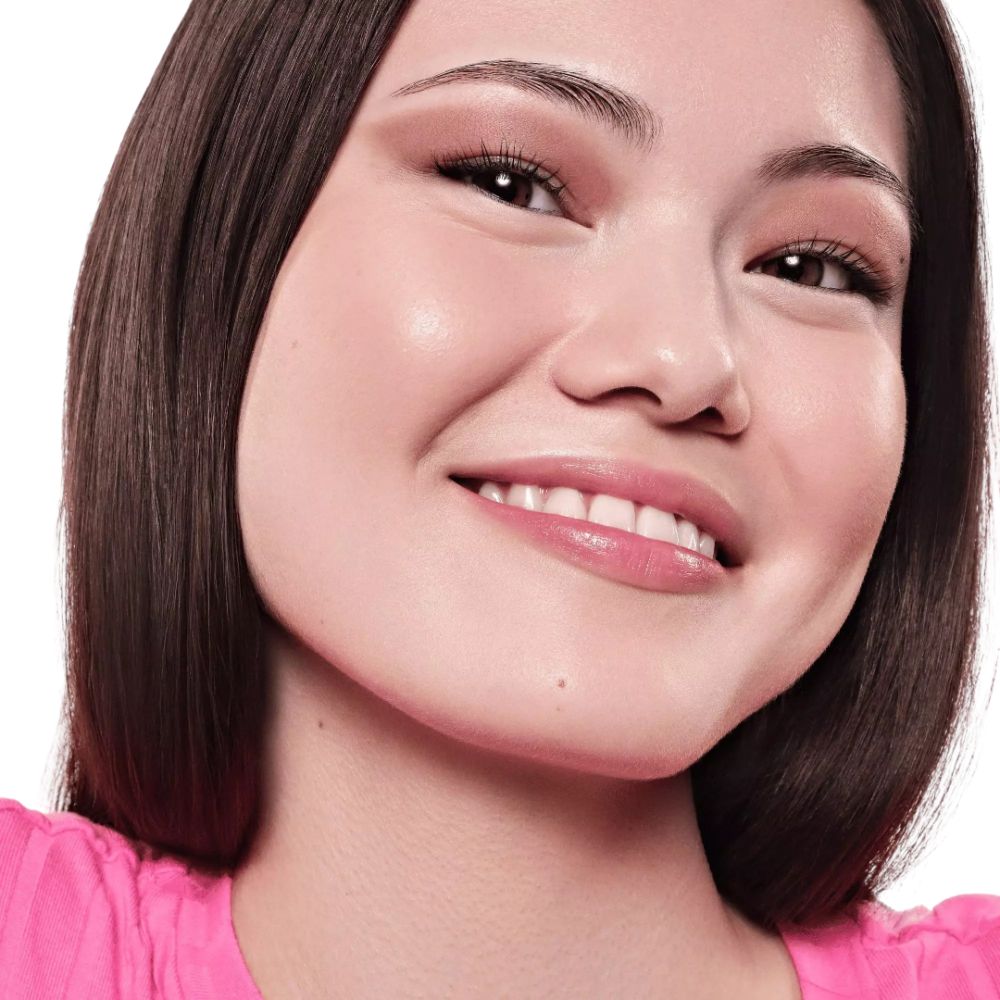 Portrait d'une femme souriante avec lèvres et joues roses. Haut rose.