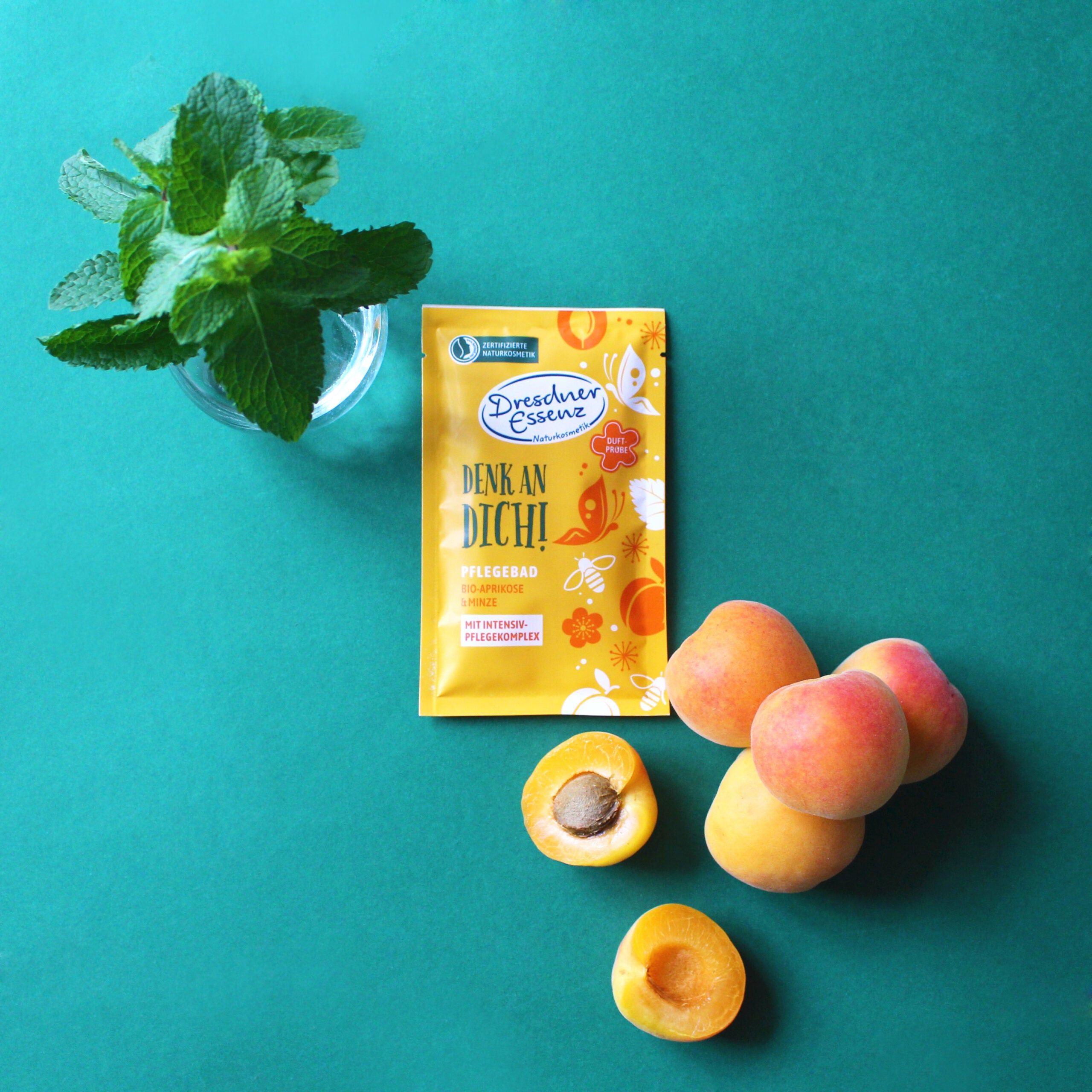 Gele productverpakking, daarnaast abrikozen en munt. Tekst: Dresdner Essenz, verzorgingsbad Bio-Abrikoos & Munt.