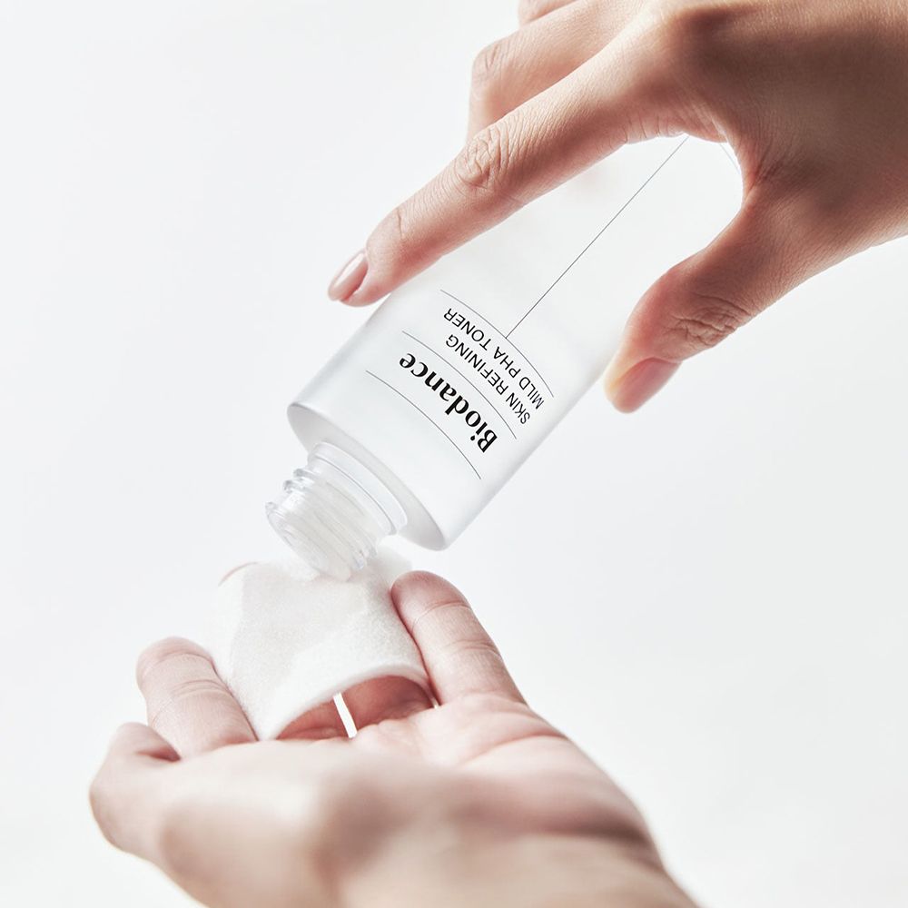 Handen houden een fles en een watje vast. Vloeistof wordt op het watje gegoten. Opschrift: Biodance.