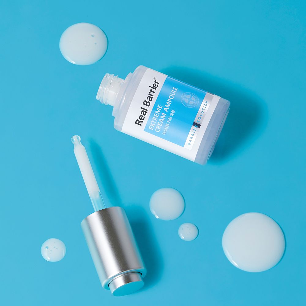 Flesje met open dop en pipet. Druppels vloeistof ernaast. Opschrift: REAL BARRIER Extreme Cream Ampoule.