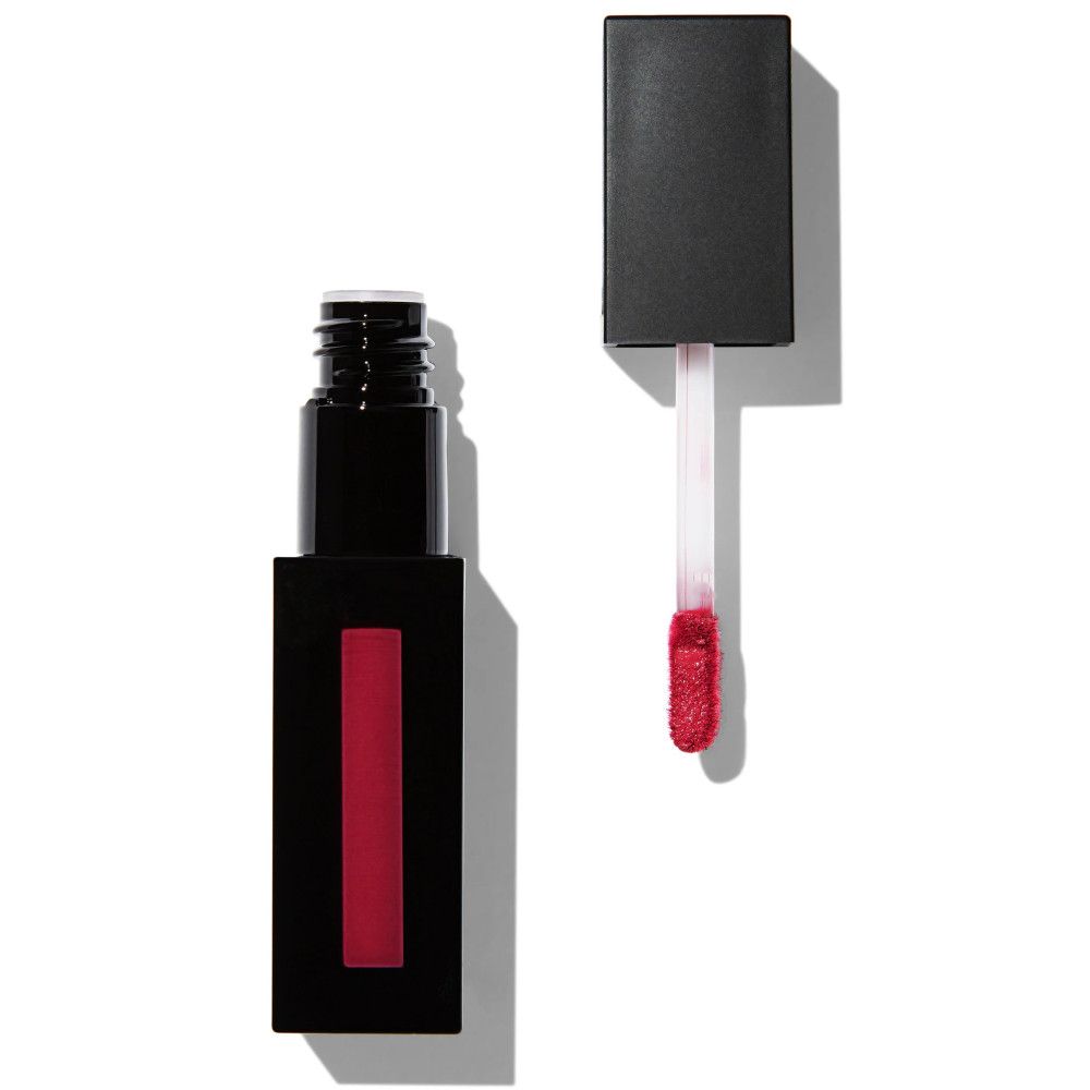 Tube de gloss noir, rectangulaire, avec contenu rouge. Le bouchon est retiré, révélant un applicateur avec de la couleur rouge.