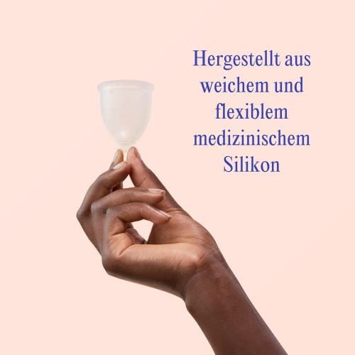 Hand die een transparante menstruatiecup vasthoudt van zachte, flexibele medische siliconen. Roze achtergrond.