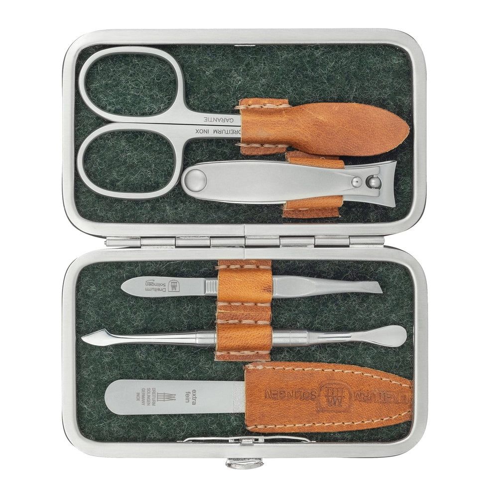 Open etui met manicuregereedschap: schaar, nagelvijl, pincet, bokkenpoot. Bruine lederen details.