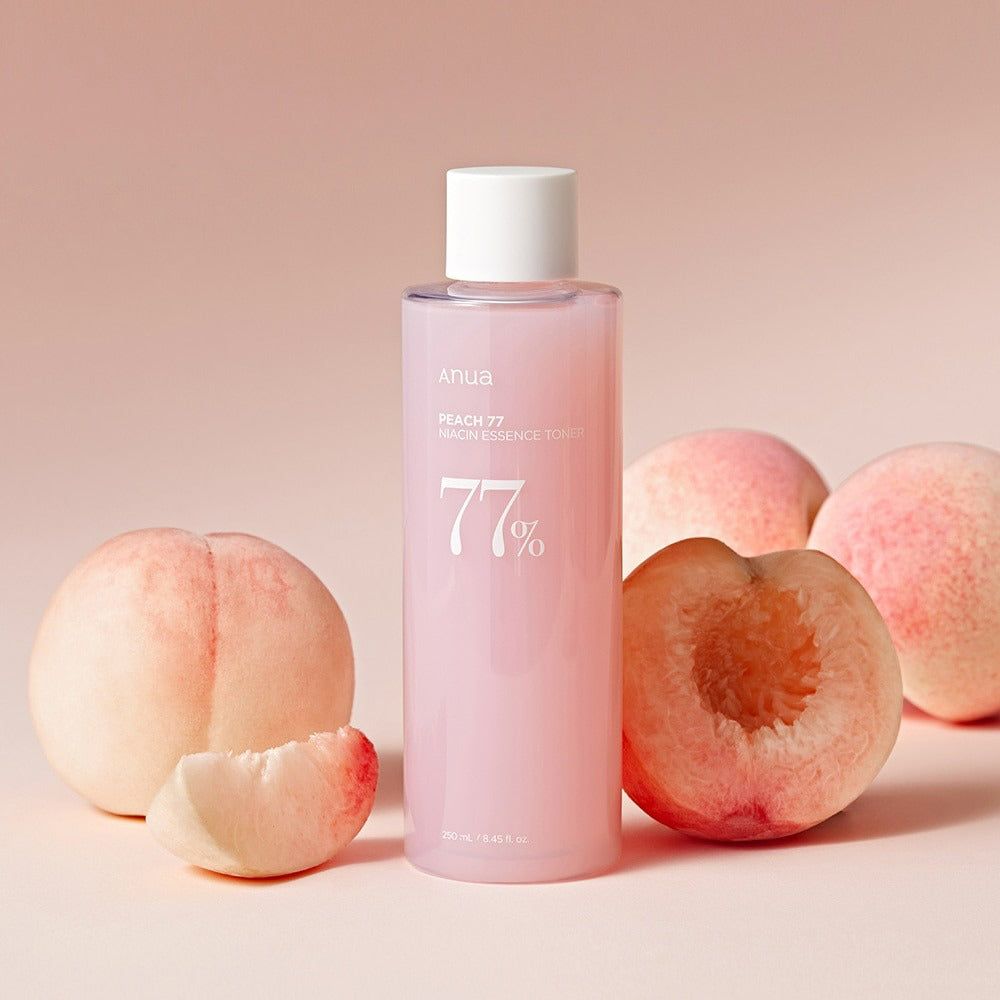 Roze fles met witte dop en perziken. Opschrift: Peach 77 Niacin Essence Toner. 77% in witte letters.