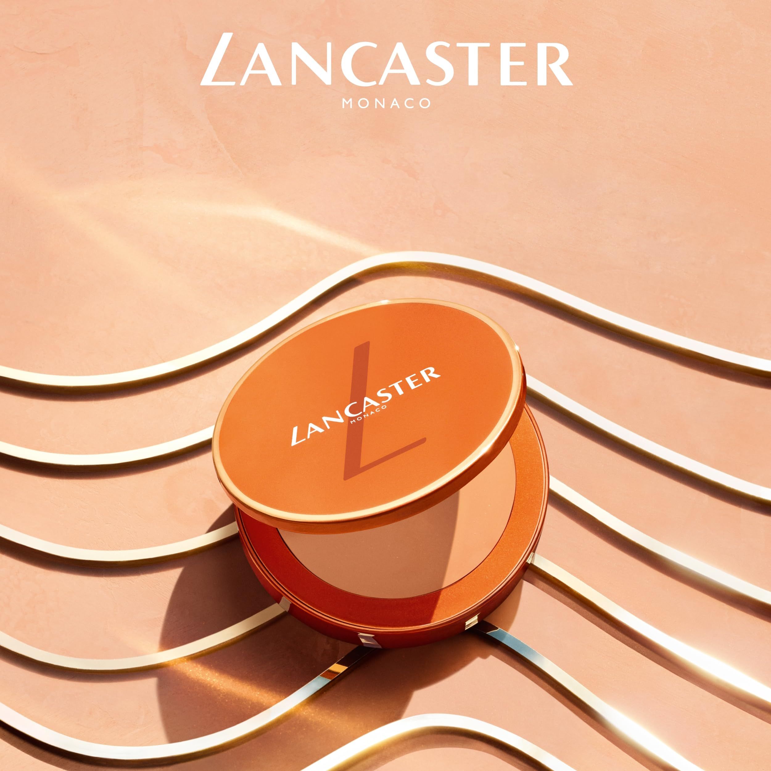 Crème solaire compacte orange ouverte. Couvercle avec logo LANCASTER. Intérieur: crème teintée. Fond: lignes dorées.