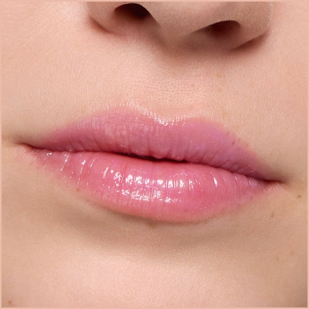Gros plan sur des lèvres recouvertes d'un baume à lèvres rose brillant.