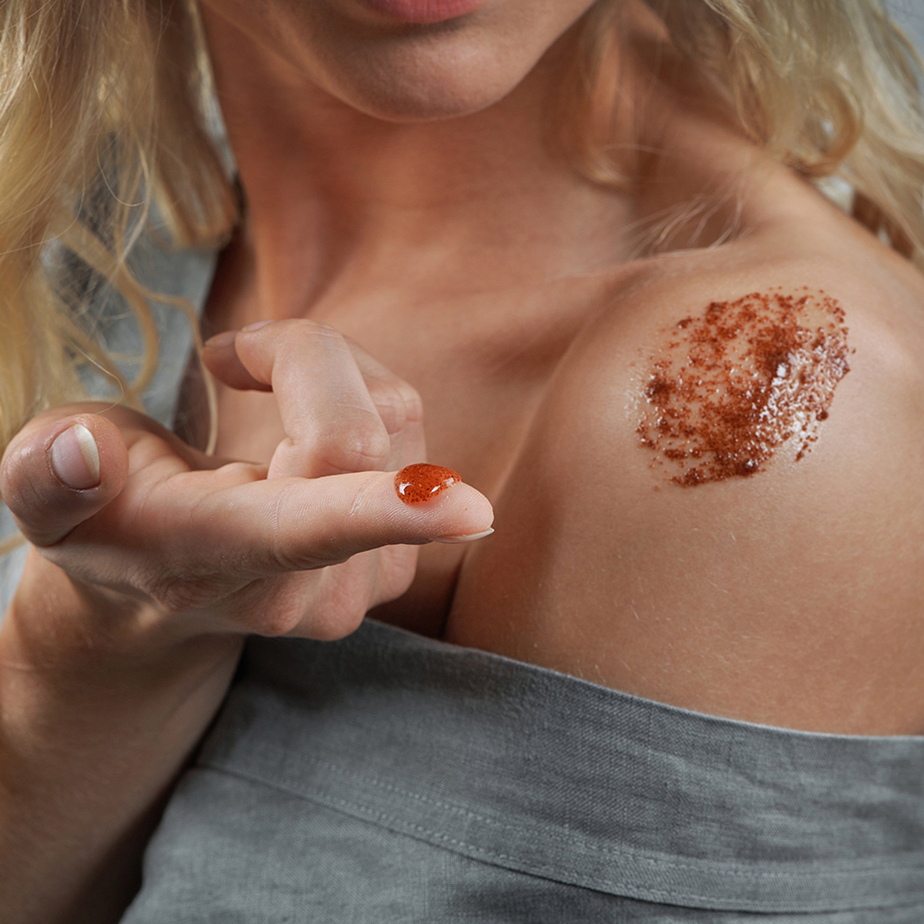 Personne appliquant un gommage sur l'épaule. Inscription : Australian Bodycare.