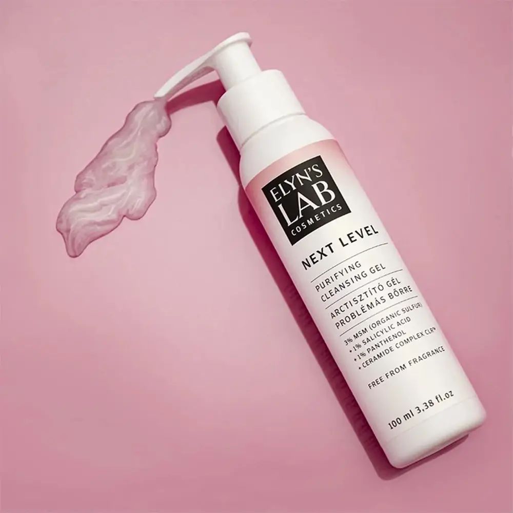 Witte fles met pomp. Roze etiket met tekst: ELYN'S LAB, NEXT LEVEL, reinigingsgel. Gel afgegeven.