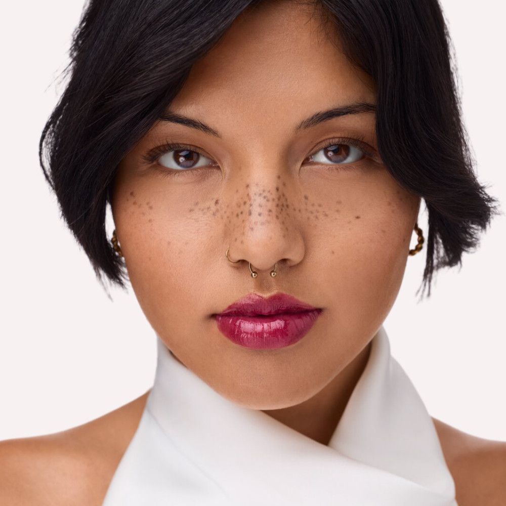 Portret van een vrouw met rode lipgloss. Ze draagt een witte sjaal en heeft sproeten in haar gezicht.