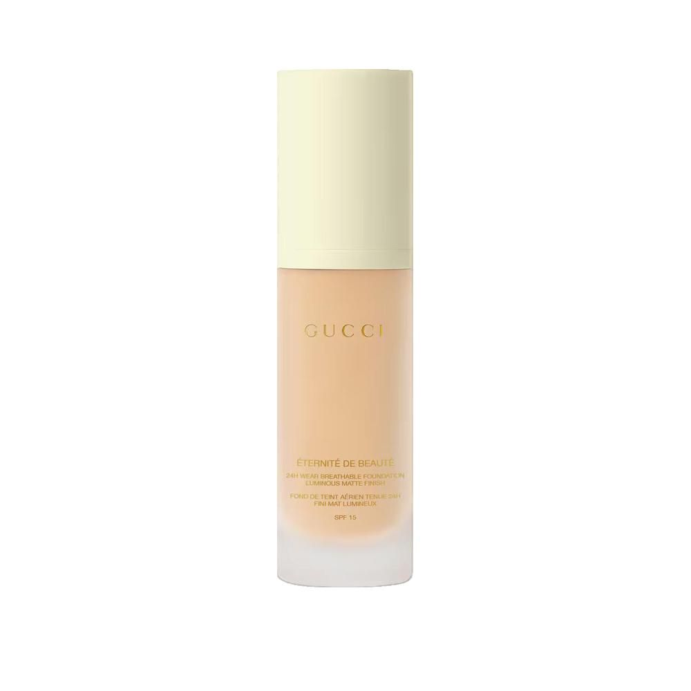 Beige foundationfles met gele dop. Opschrift: Gucci, Éternité de Beauté. Hoge dekking, SPF 15.
