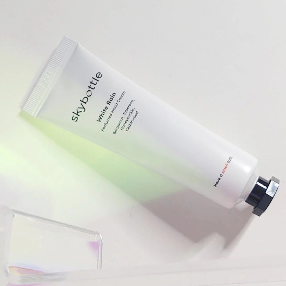 Tube blanche avec bouchon noir. Inscription: skybottle, White Rain, crème pour les mains. Ingrédients: bergamote, tubéreuse, chèvrefeuille, bois de cèdre.