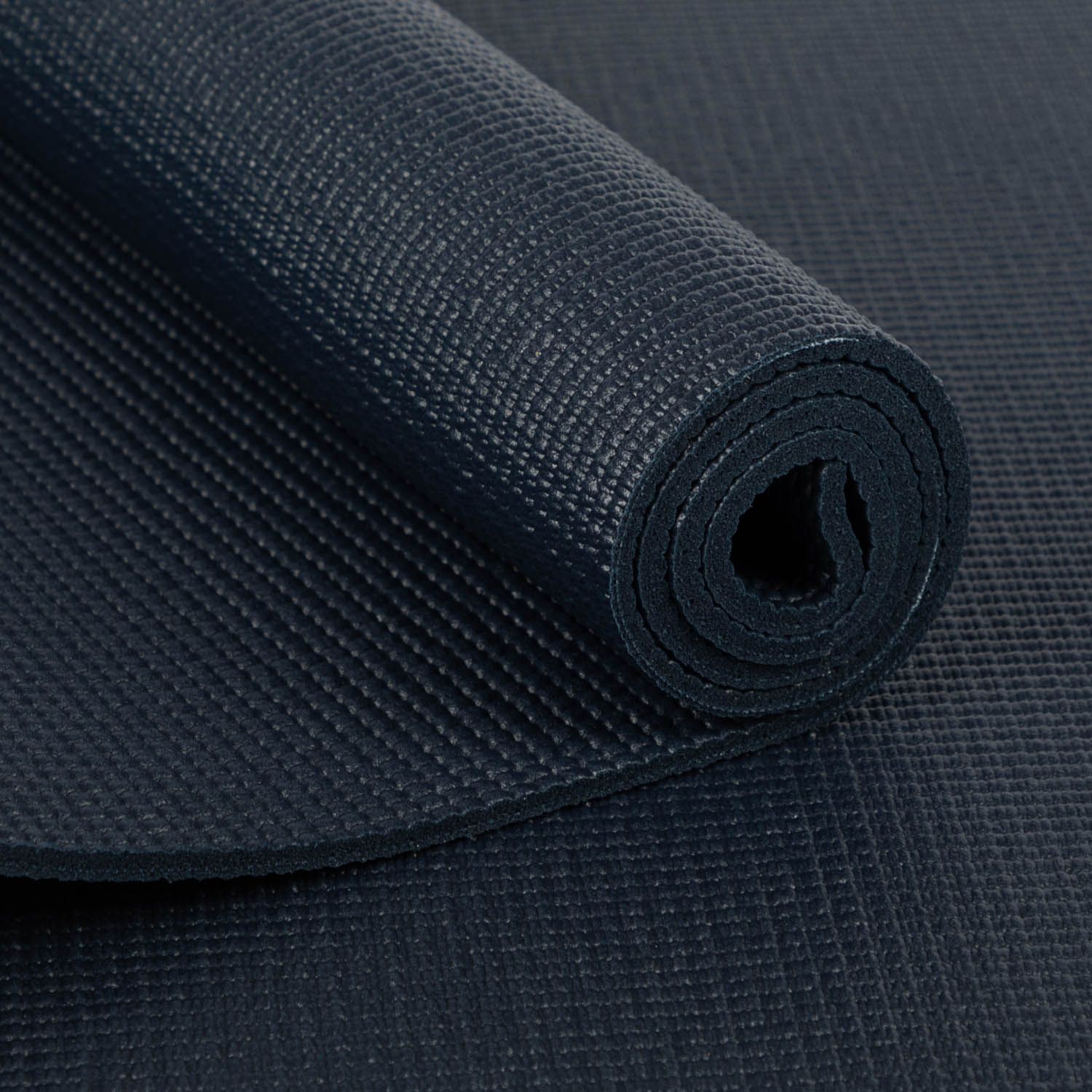 Close-up van een opgerolde donkerblauwe yogamat. Het oppervlak is gestructureerd.