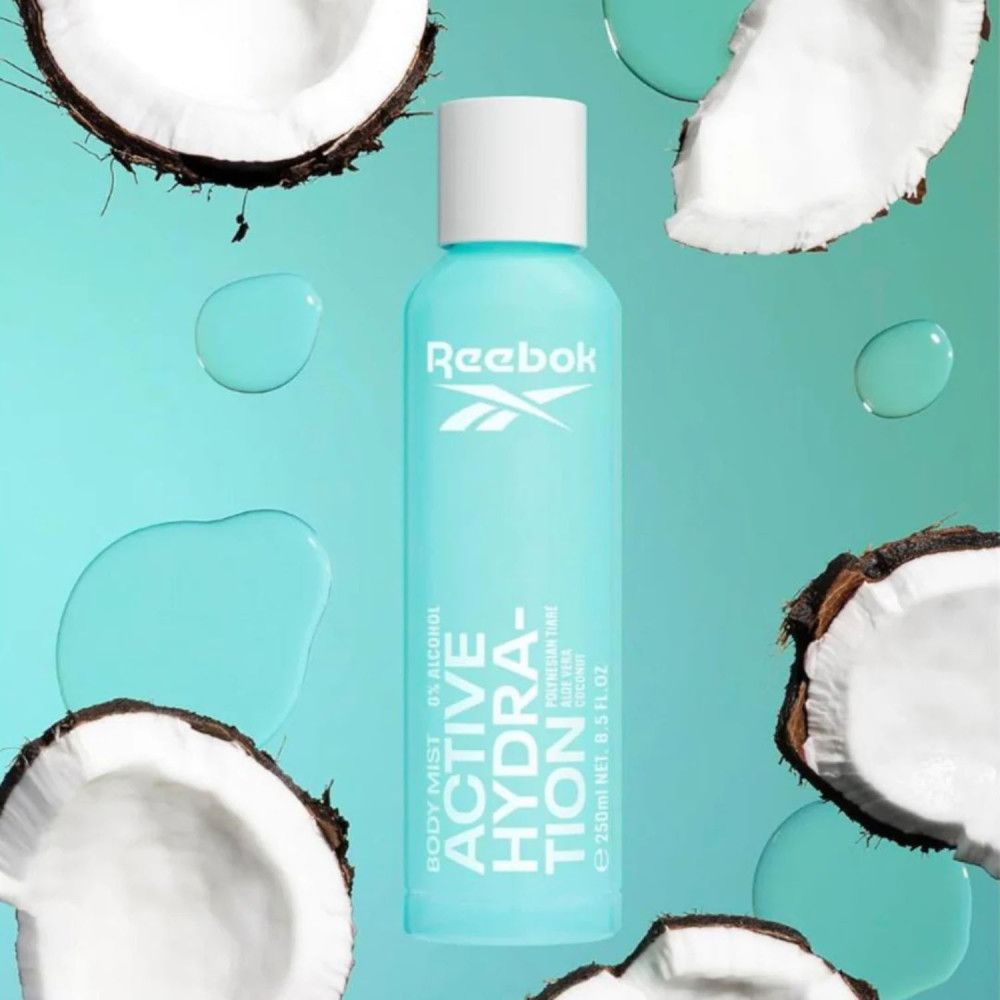 Spray corporel bleu clair avec bouchon blanc. Logo Reebok et texte 'Active Hydration'. Morceaux de noix de coco et gouttes d'eau.