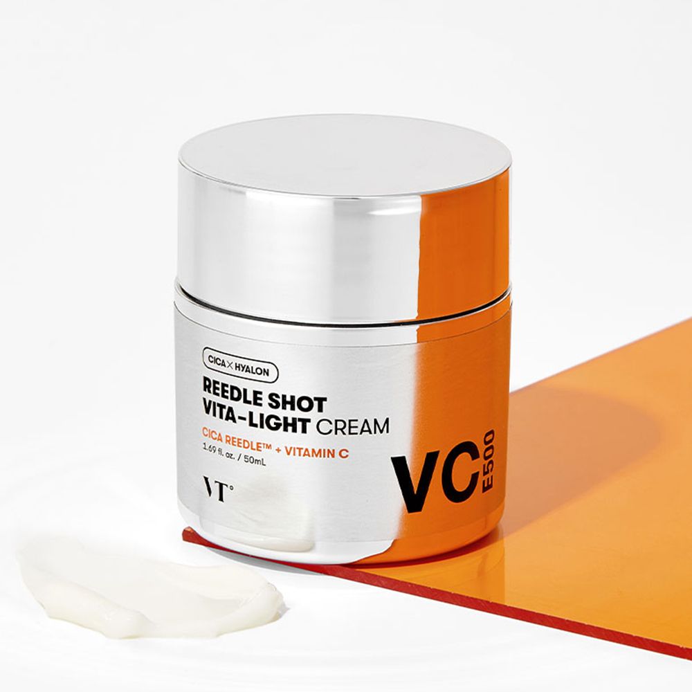 Crèmepot met zilveren deksel. Opschrift: REEDLE SHOT VITA-LIGHT CREAM, CICA REEDLE + Vitamine C, VC E500. Merk: VT. Oranje achtergrond.