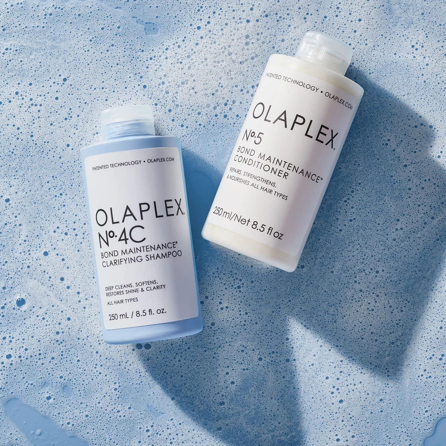 Twee flessen Olaplex shampoo en conditioner. Opschrift: Olaplex No. 4C Bond Maintenance Clarifying Shampoo en No. 5 Bond Maintenance Conditioner.