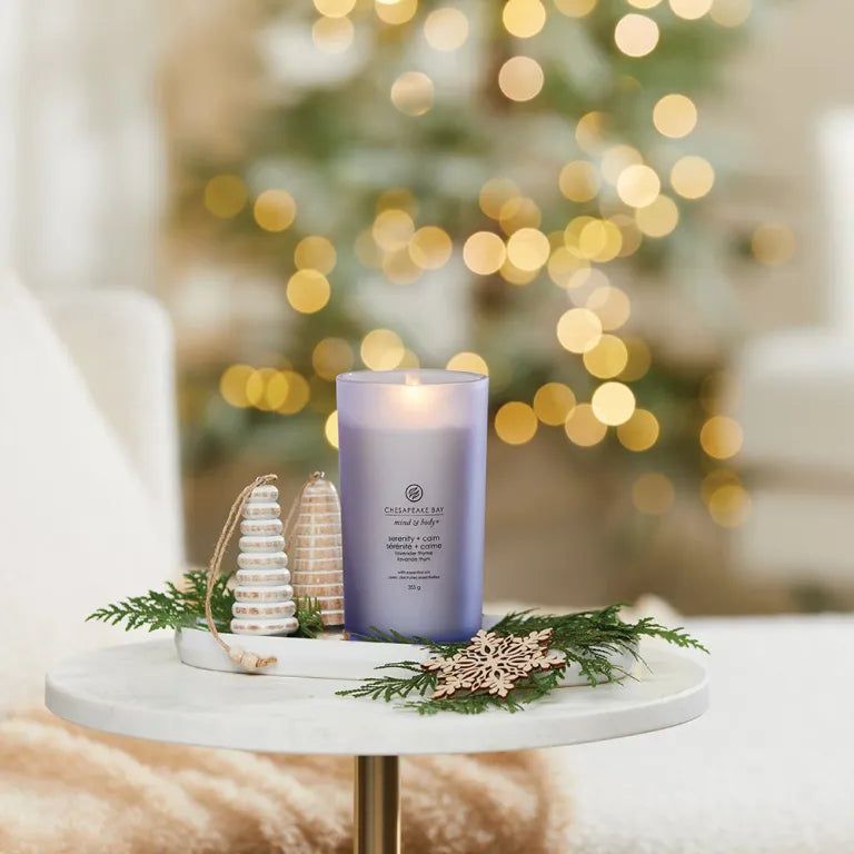 Bougie allumée en verre bleu. Inscription: Chesapeake Bay, mind & body, sérénité + calme. Décoration: plateau, branches de sapin, ornements en bois.