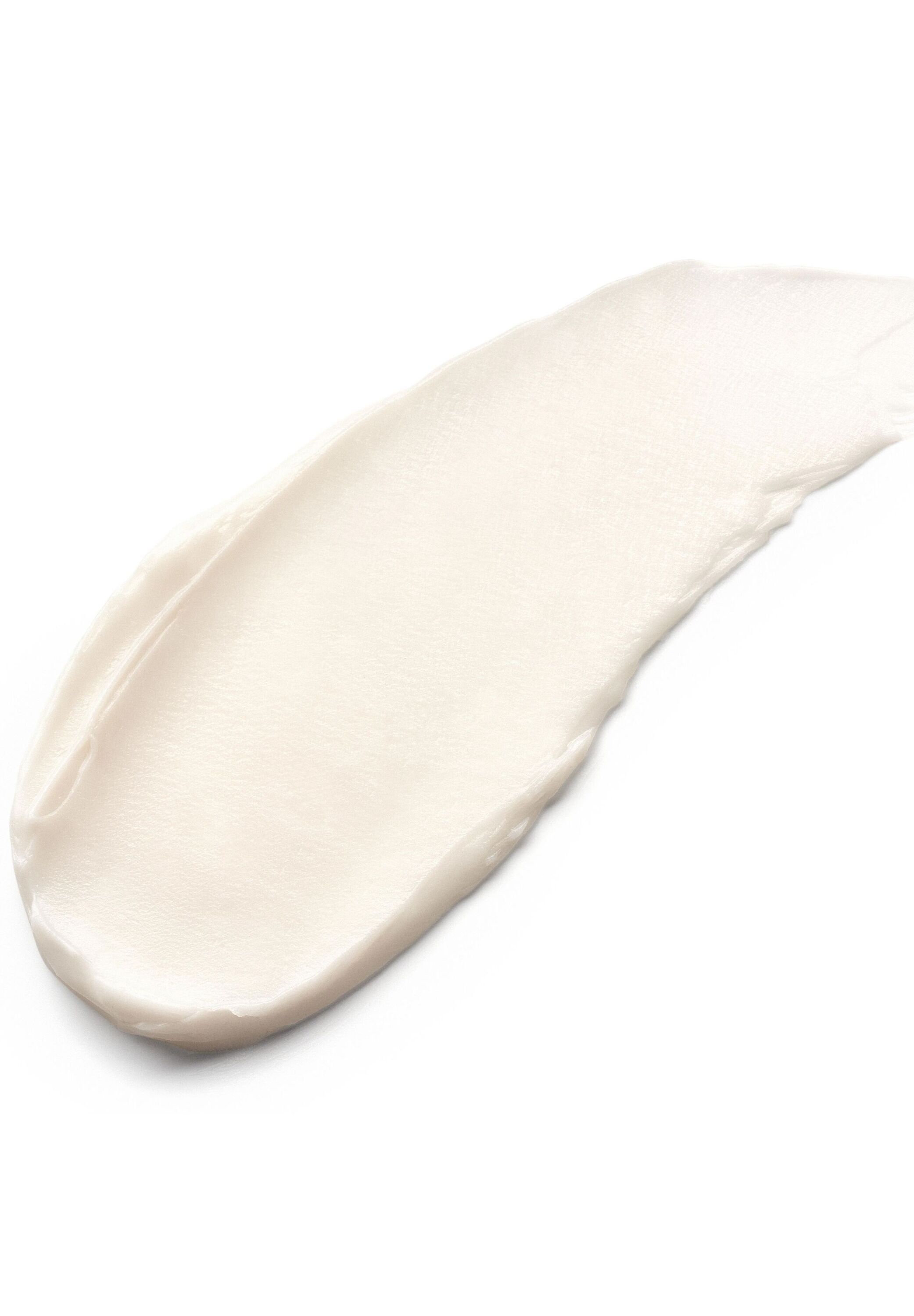 Uitgesmeerde crème op witte achtergrond. Crèmekleurige textuur.