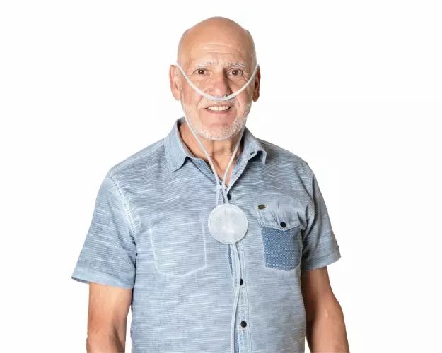 Een oudere man draagt een zuurstofbril met een reservoir.