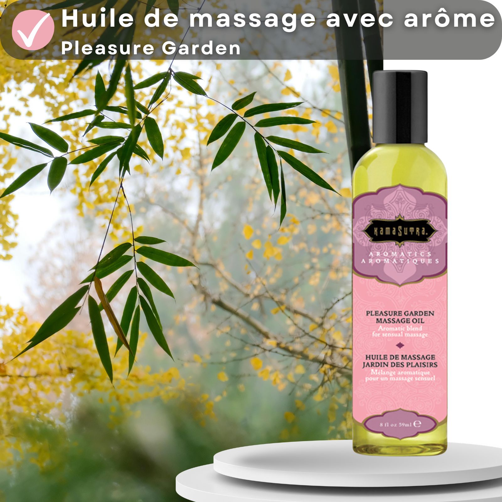 Huile de massage Kamasutra avec arôme Pleasure Garden. Bouteille sur surface blanche, fond avec feuilles et bambou.