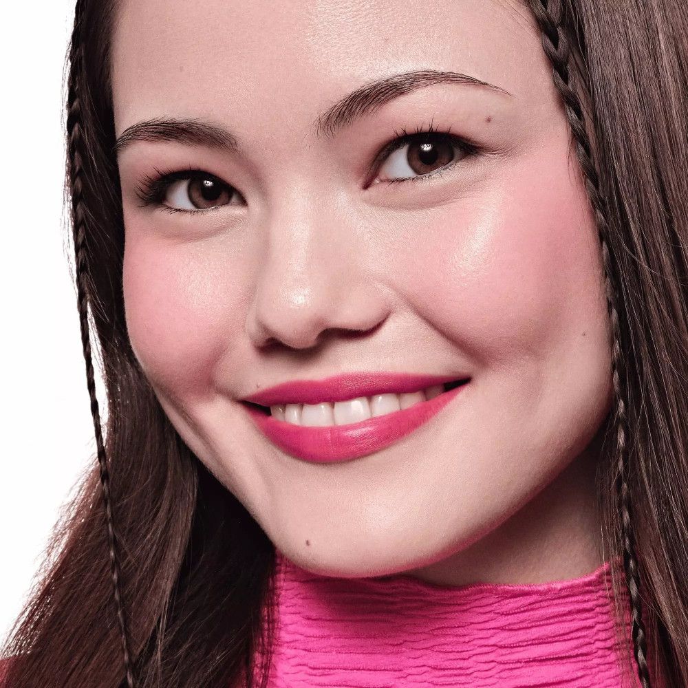 Portret van een vrouw met roze wangen en lippen. Ze draagt vlechten. Huidtint en make-up zichtbaar.