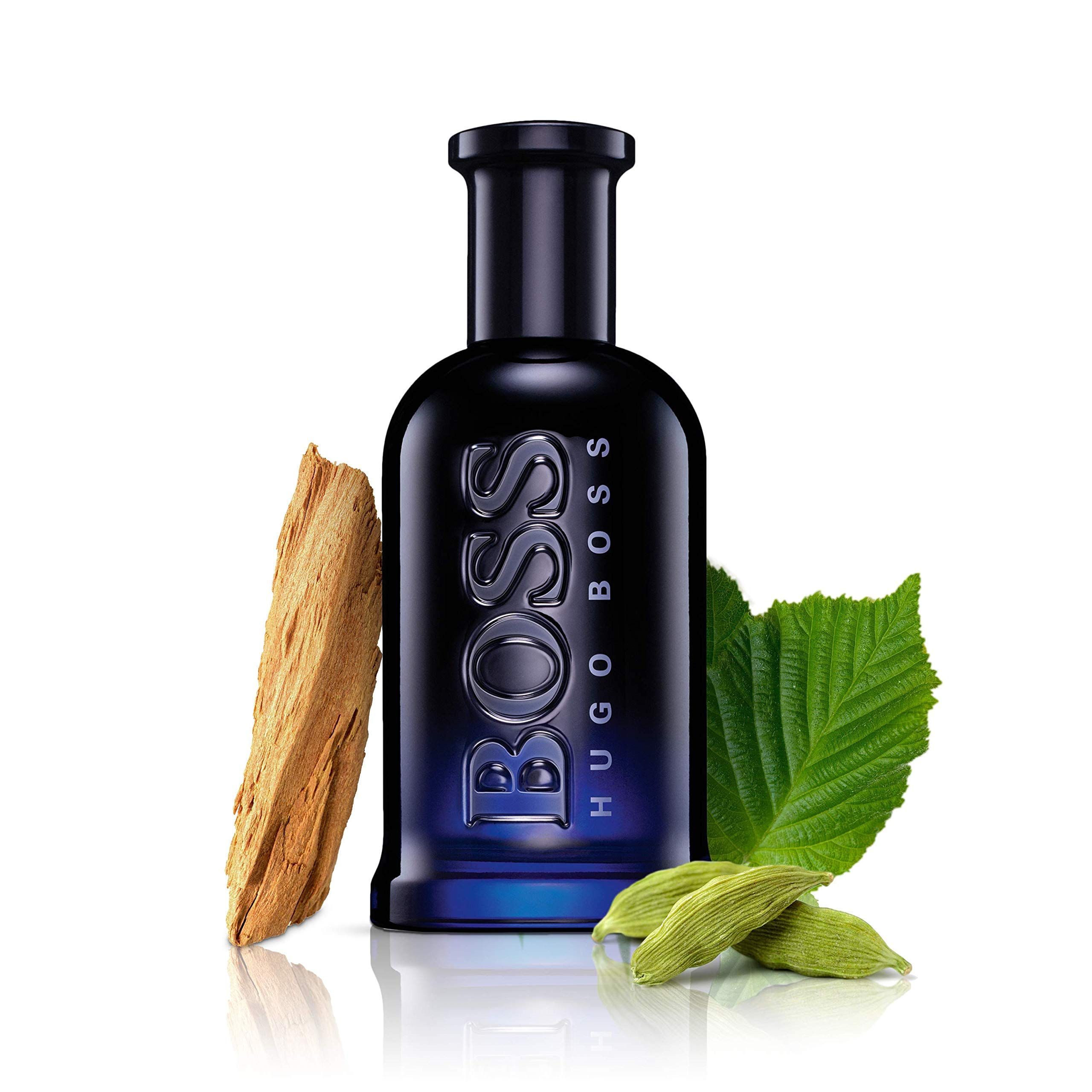 Donkerblauwe glazen fles met BOSS HUGO BOSS opschrift, omringd door hout, bladeren en kardemom.