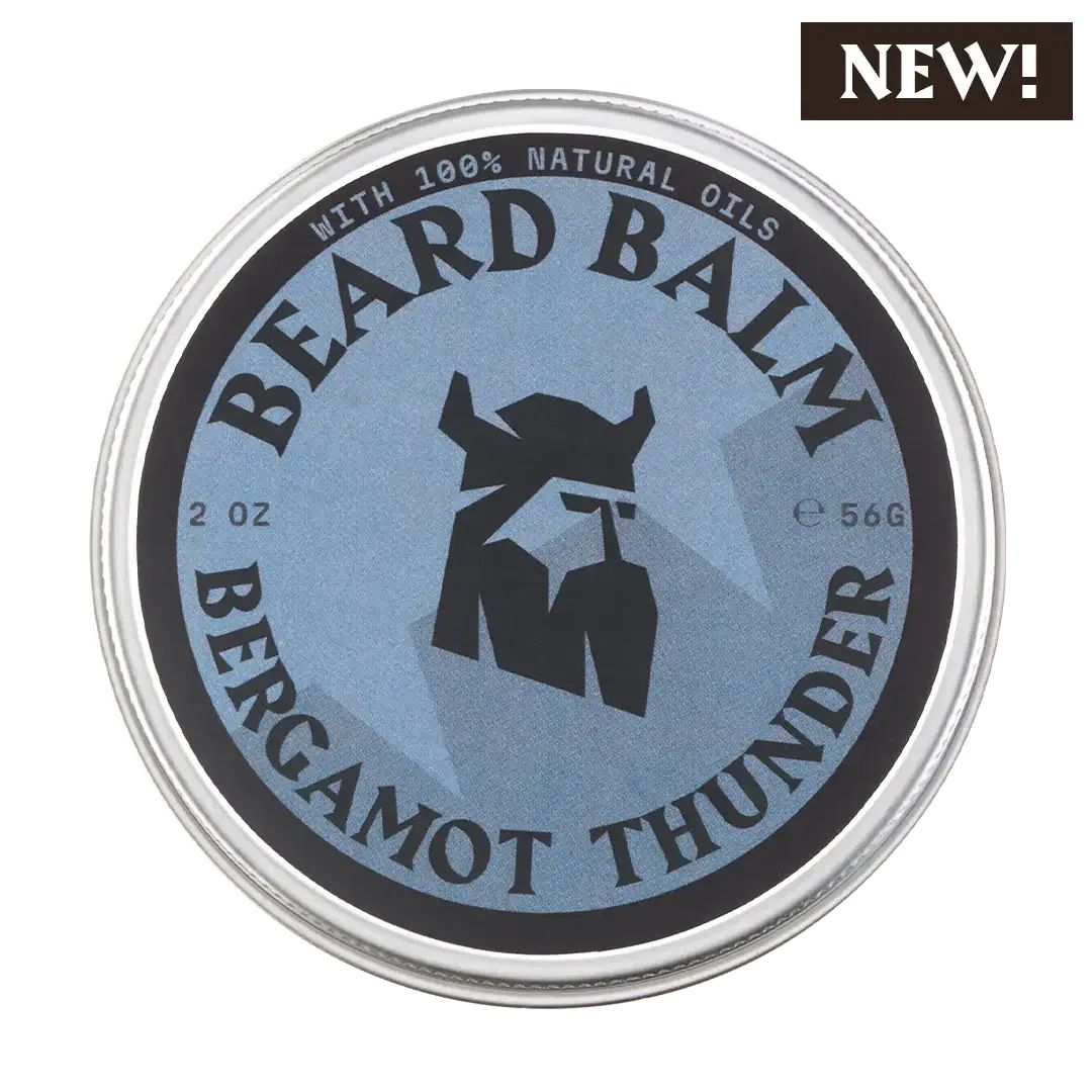 Boîte métallique ronde avec étiquette bleue. Inscription: BEARD BALM, BERGAMOT THUNDER, 2 OZ, 56G. Logo: tête de Viking. Avec mention «NEW!»