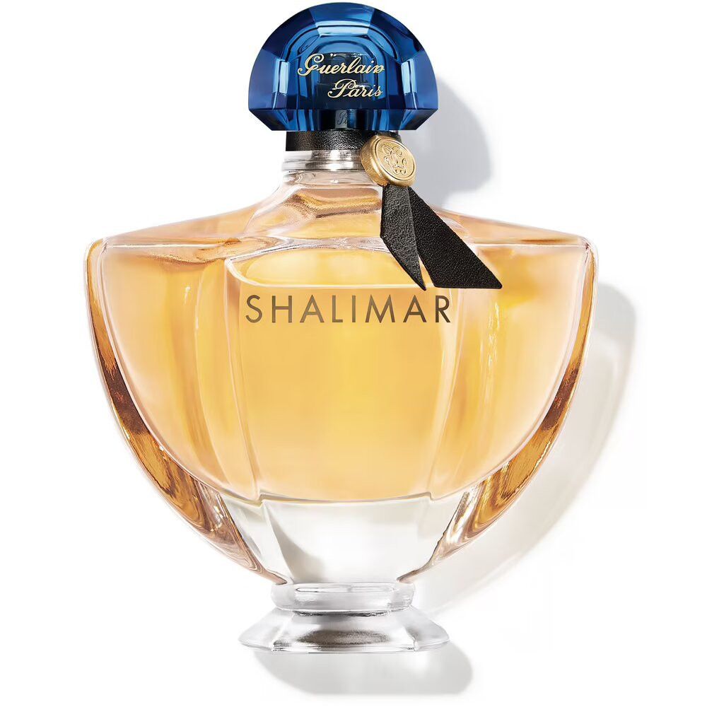Flacon de parfum avec bouchon bleu et ruban noir. Étiquette dorée avec texte. Flacon transparent avec liquide jaunâtre.