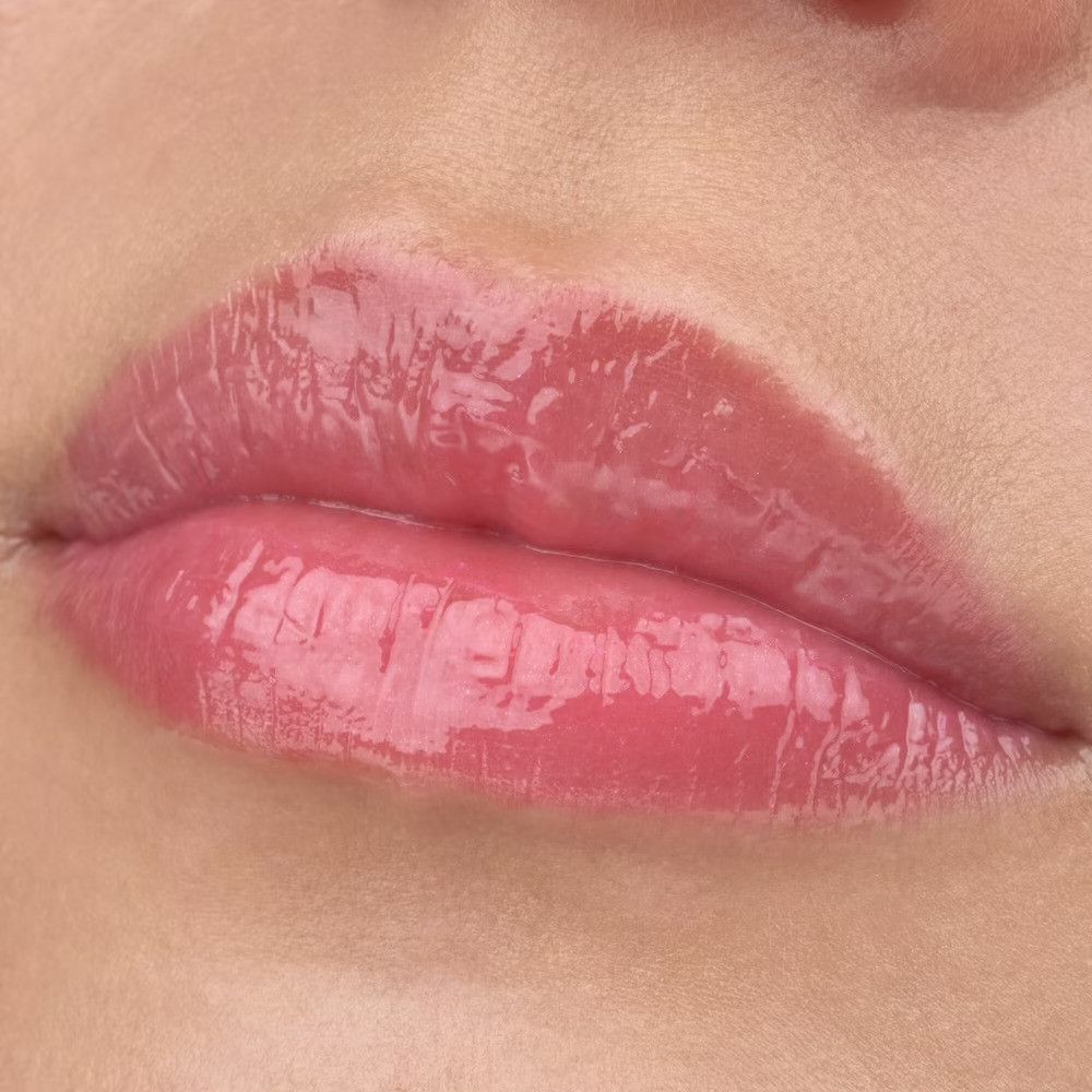 Gros plan sur des lèvres avec un gloss rose brillant.