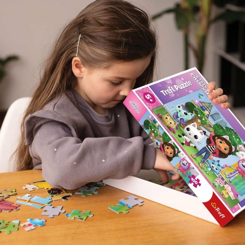 Kind opent puzzeldoos Gabby's Magic House. Puzzelstukjes en doos met Gabby en katten.