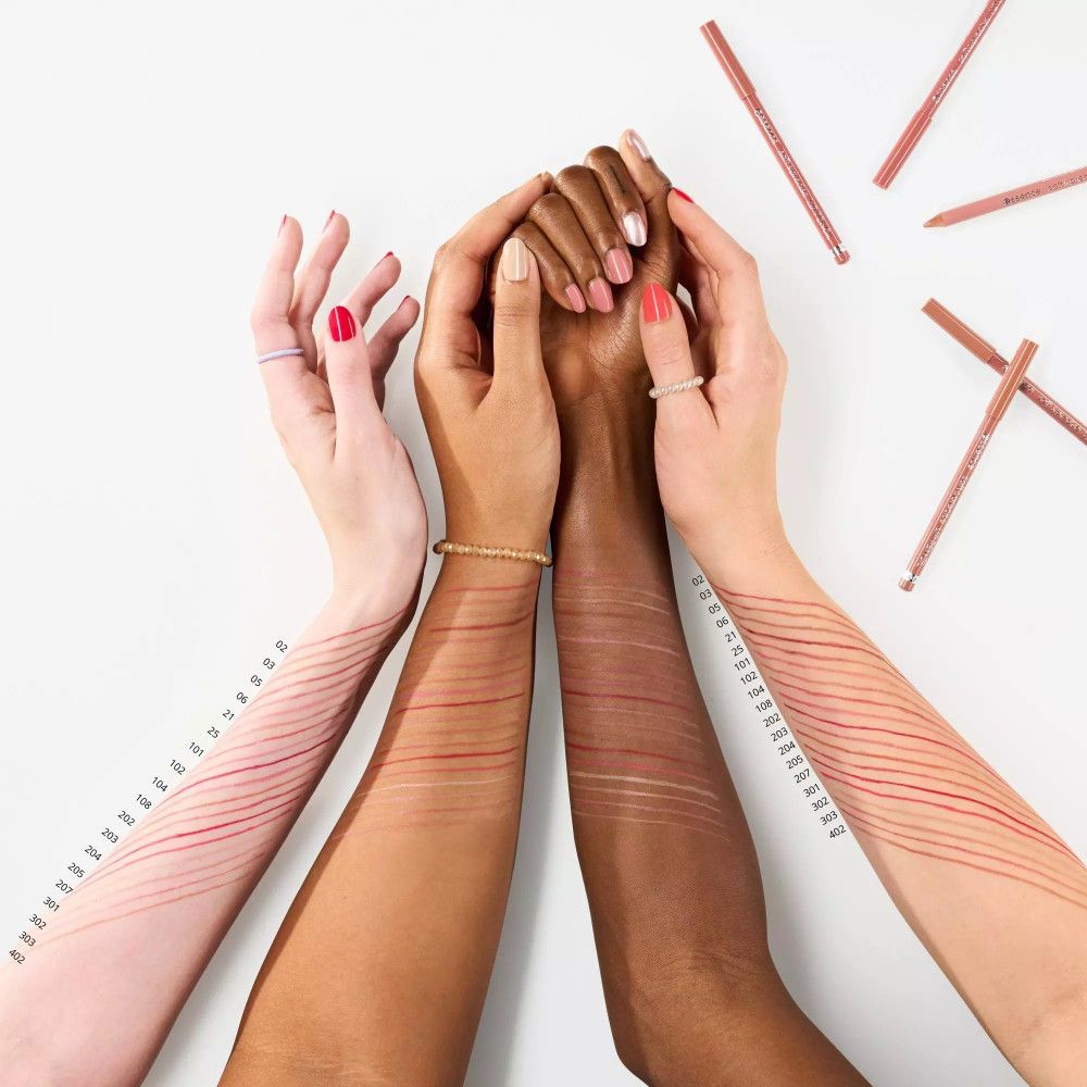 Armen met lippenstiftstreken in verschillende huidtinten. Lippenpotloden ernaast.