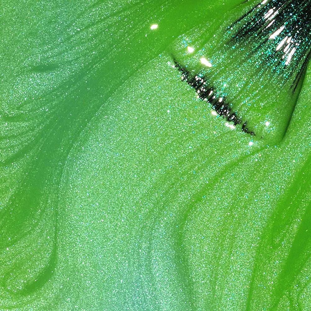 Groene nagellak met glitter. De kwast is gedeeltelijk zichtbaar.