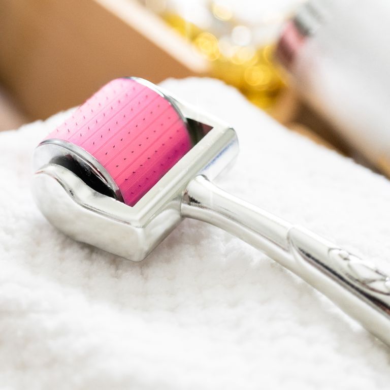 Close-up van een CIT Face Roller met roze rol op een witte handdoek.