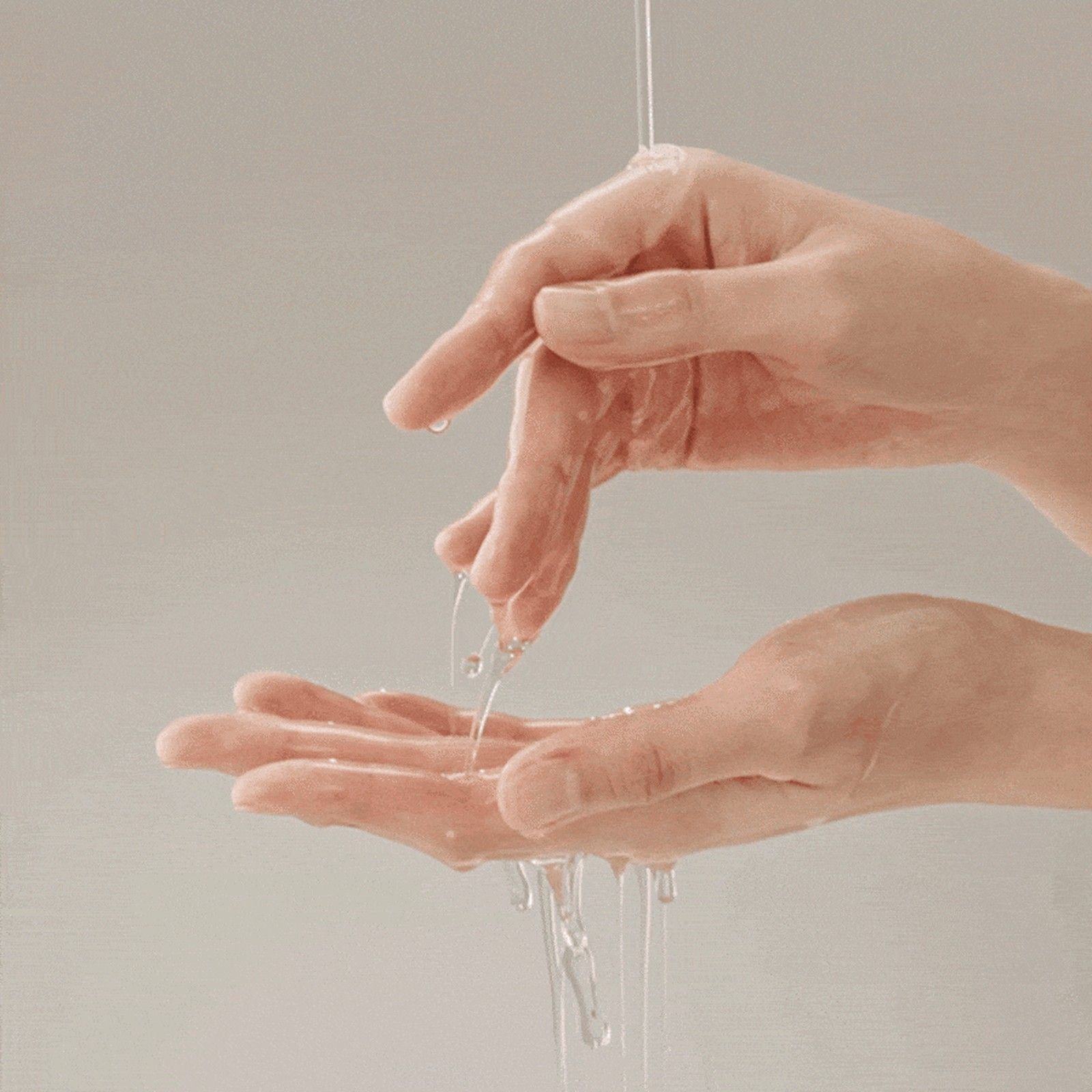 Un liquide clair tombe des doigts d'une main dans l'autre.